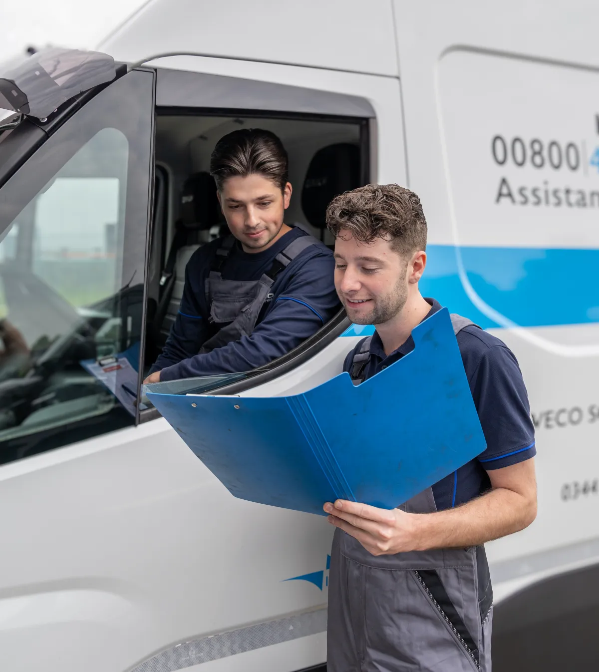 Twee monteurs van IVECO Schouten overleggen bij een servicebus.