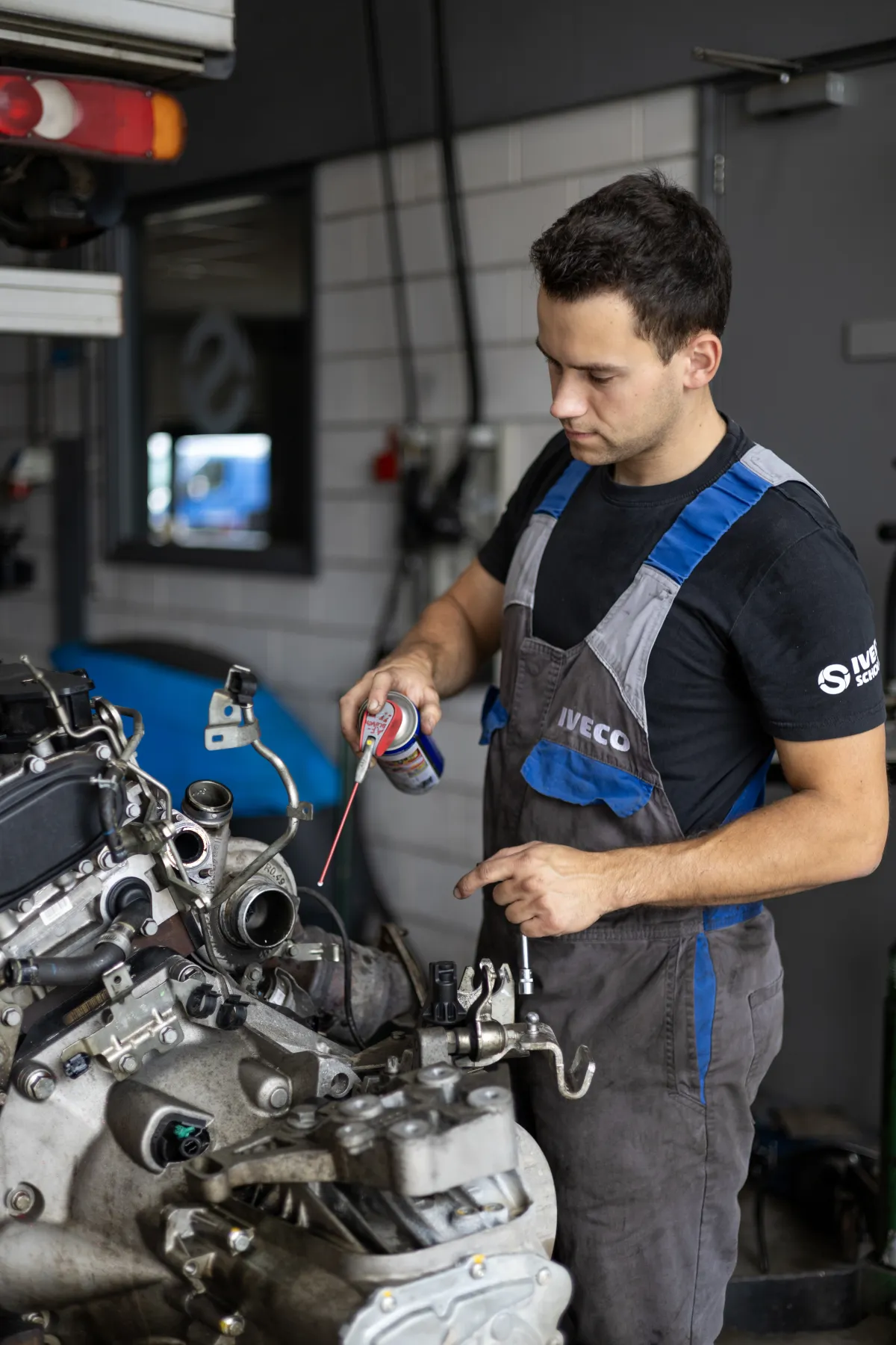 Monteur spuit smeermiddel op een losgekoppelde motor.