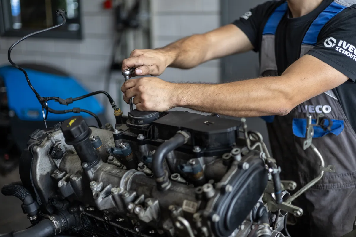 Monteur draait met een dopsleutel aan een losgekoppelde motor.