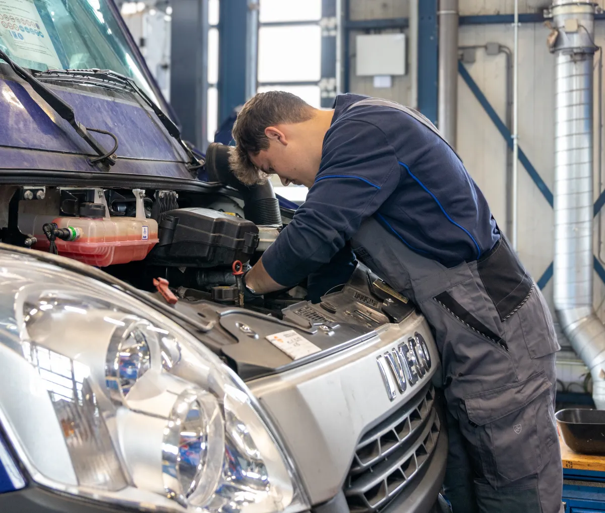 Monteur werkt aan de motor van een bestelwagen.