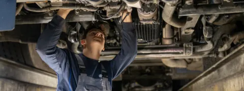 Monteur aan het sleutelen onder voertuig